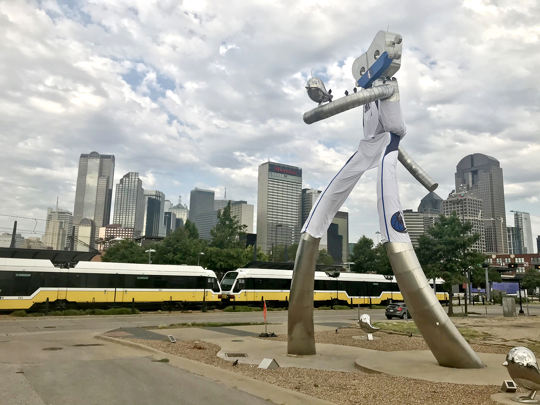 A DART train passes by Deep Ellum Station next to The Traveling Man sculpture in Dallas.